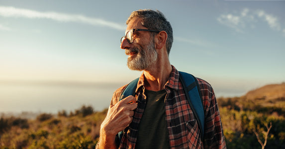 A man in his late fifties walking a sunlit trail, moving with ease